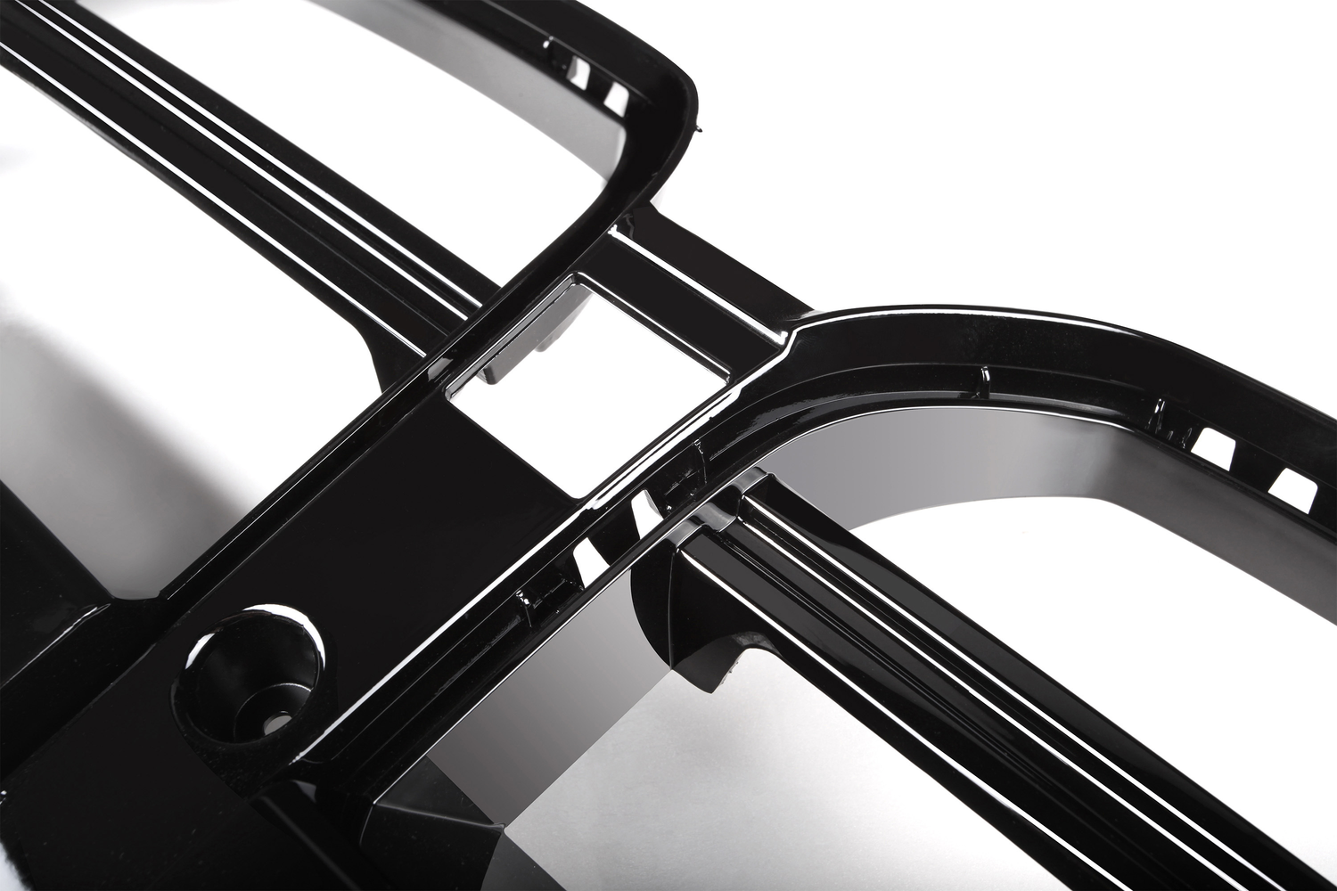 Black, glossy plastic car grille features multiple intersecting bars and rectangular openings, angled diagonally. Set against a white background, evoking a sleek, modern automotive part.