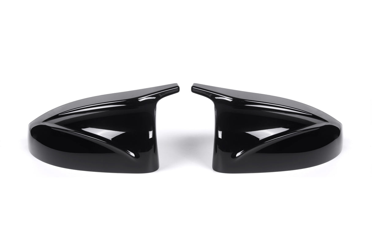 Two sleek black car side mirror covers face each other, reflecting light. They rest on a plain white background, showcasing their glossy finish and aerodynamic design.