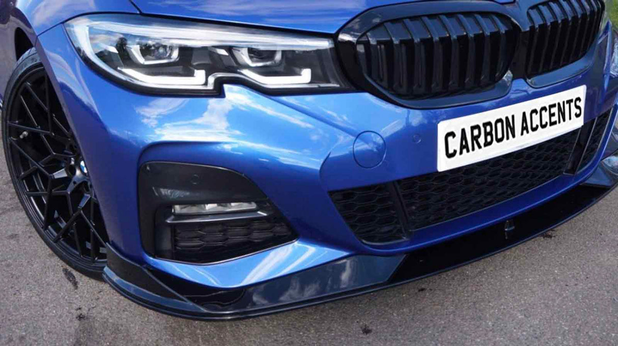 A blue car with a front view displaying sleek headlights and a prominent grille. It is parked on a pavement. The license plate reads "CARBON ACCENTS."