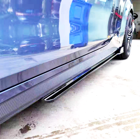 A blue car with a glossy surface reflects nearby objects, including a blue container, parked on a concrete floor in a garage.