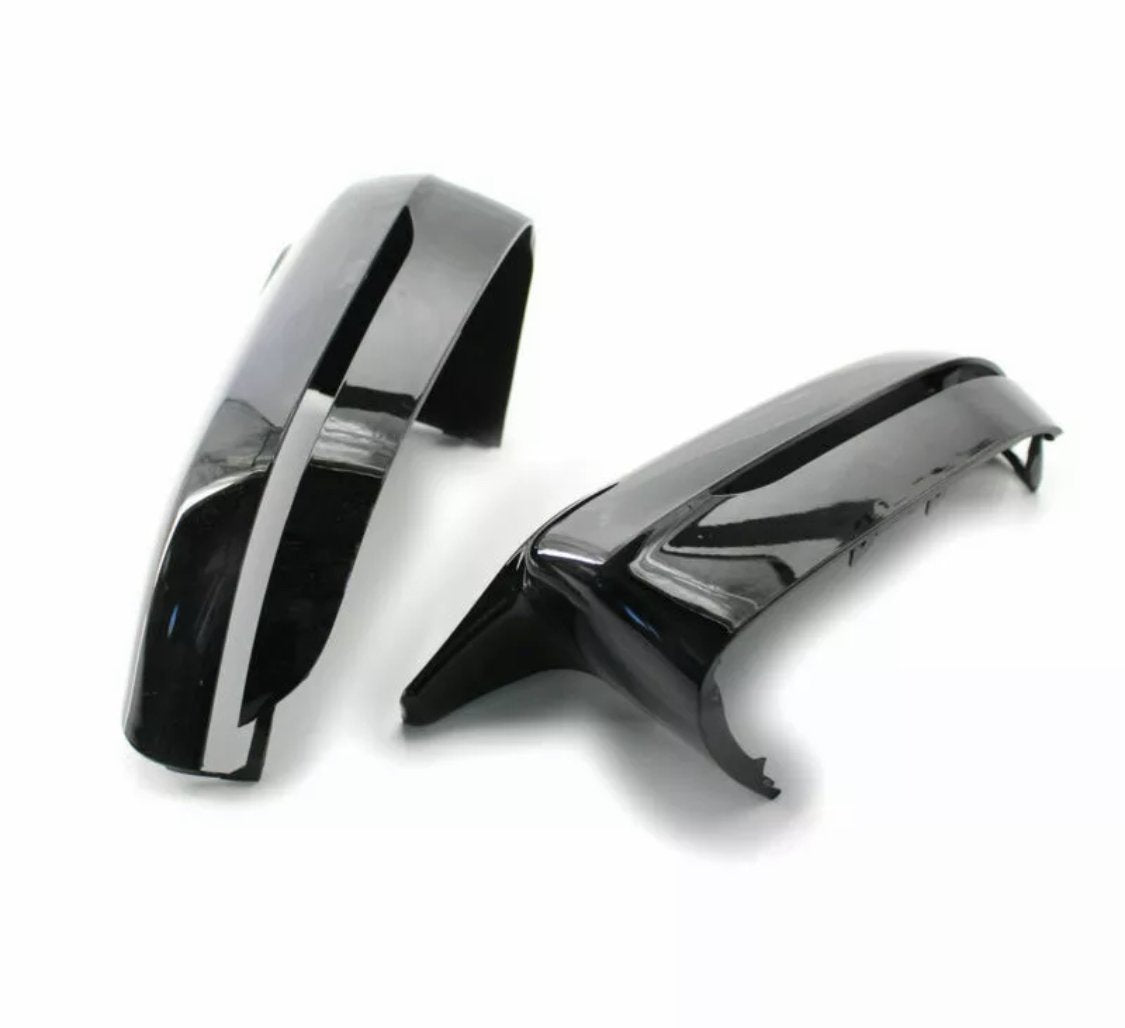 Two glossy black car mirror covers rest on a plain white surface, showcasing their sleek, curved design and reflective finish.