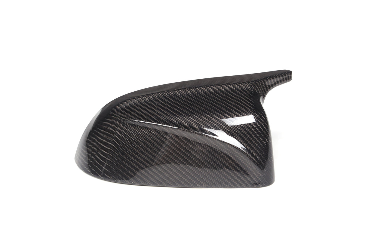 A glossy, carbon fiber car side mirror cover is positioned against a plain white background. It features a textured pattern typical of carbon fiber materials, showcasing aerodynamic design.