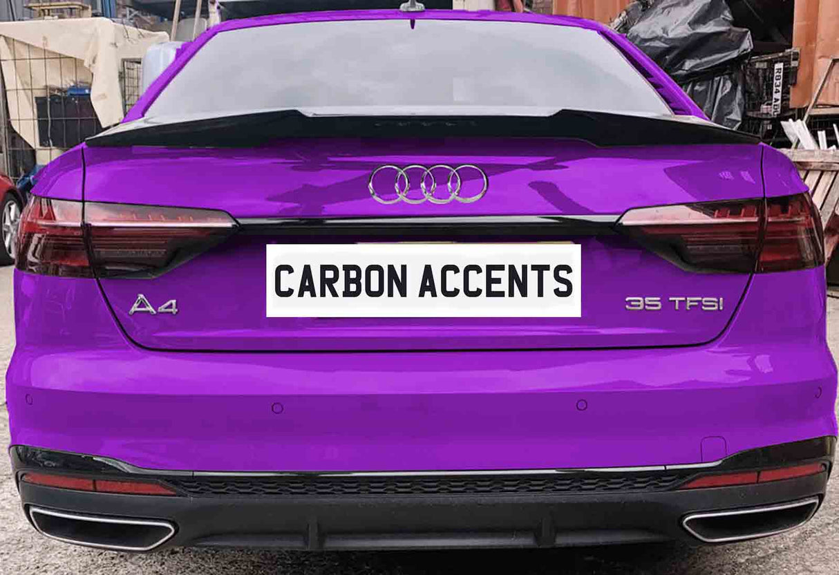 A purple Audi A4 with "35 TFSI" badge is parked, displaying the license plate text "CARBON ACCENTS." The vehicle is in a workshop area with various items in the background.