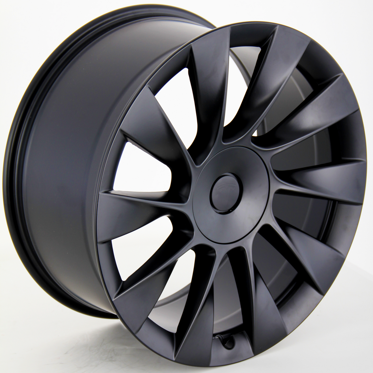 A matte black alloy wheel with multiple spokes is positioned upright. It rests on a clean, white surface, showcasing its sleek, modern design against a plain background.