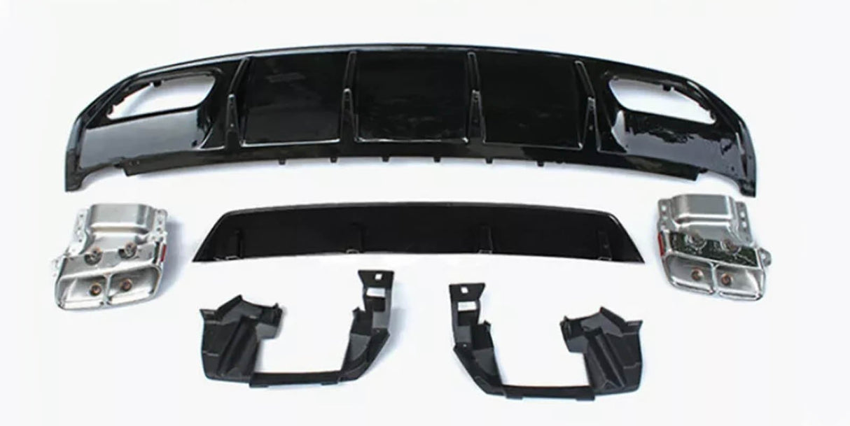 Assorted car parts, including a large black bumper and metallic components, are laid out on a plain white surface, arranged neatly for display or assembly.