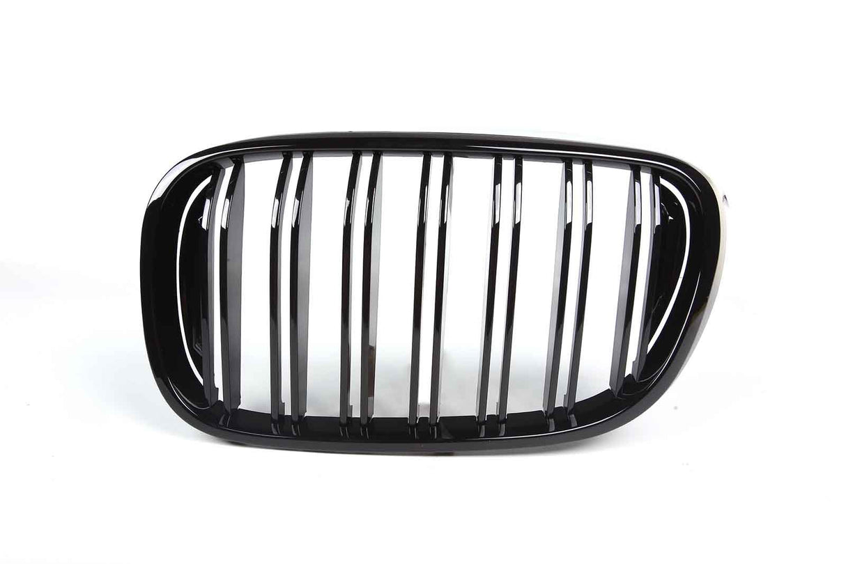 A shiny black car grille with vertical slats is displayed against a plain white background, emphasizing its sleek design.