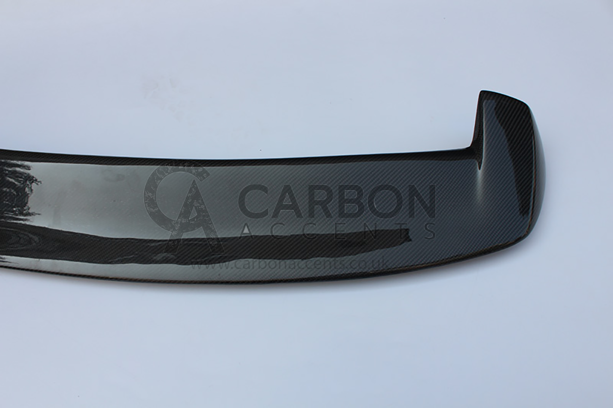Carbon fiber car spoiler on a white background, featuring a subtle weave pattern and sleek design. Text reads: "CARBON ACCENTS www.carbonaccents.co.uk."