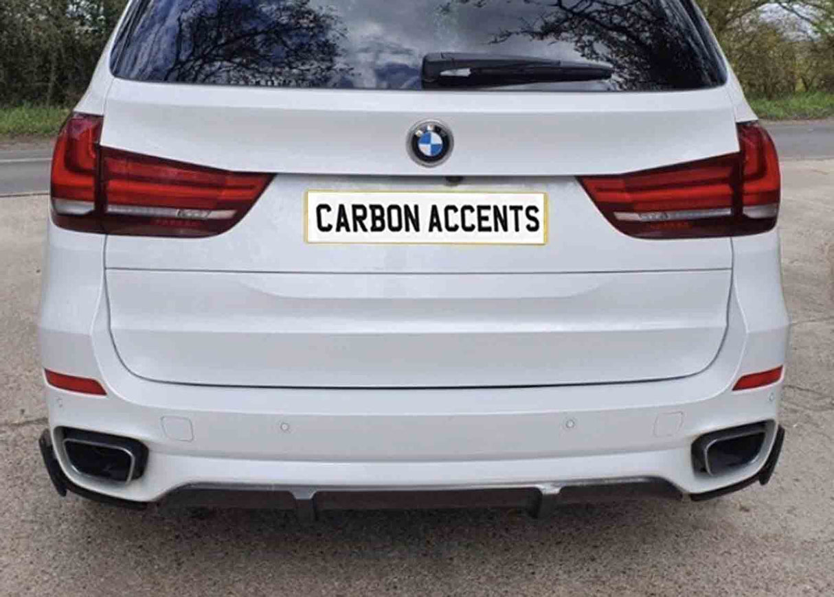 A white SUV's rear showcases taillights and exhaust pipes; the license plate bears the text "CARBON ACCENTS" in bold. The vehicle is parked outdoors on a paved surface.