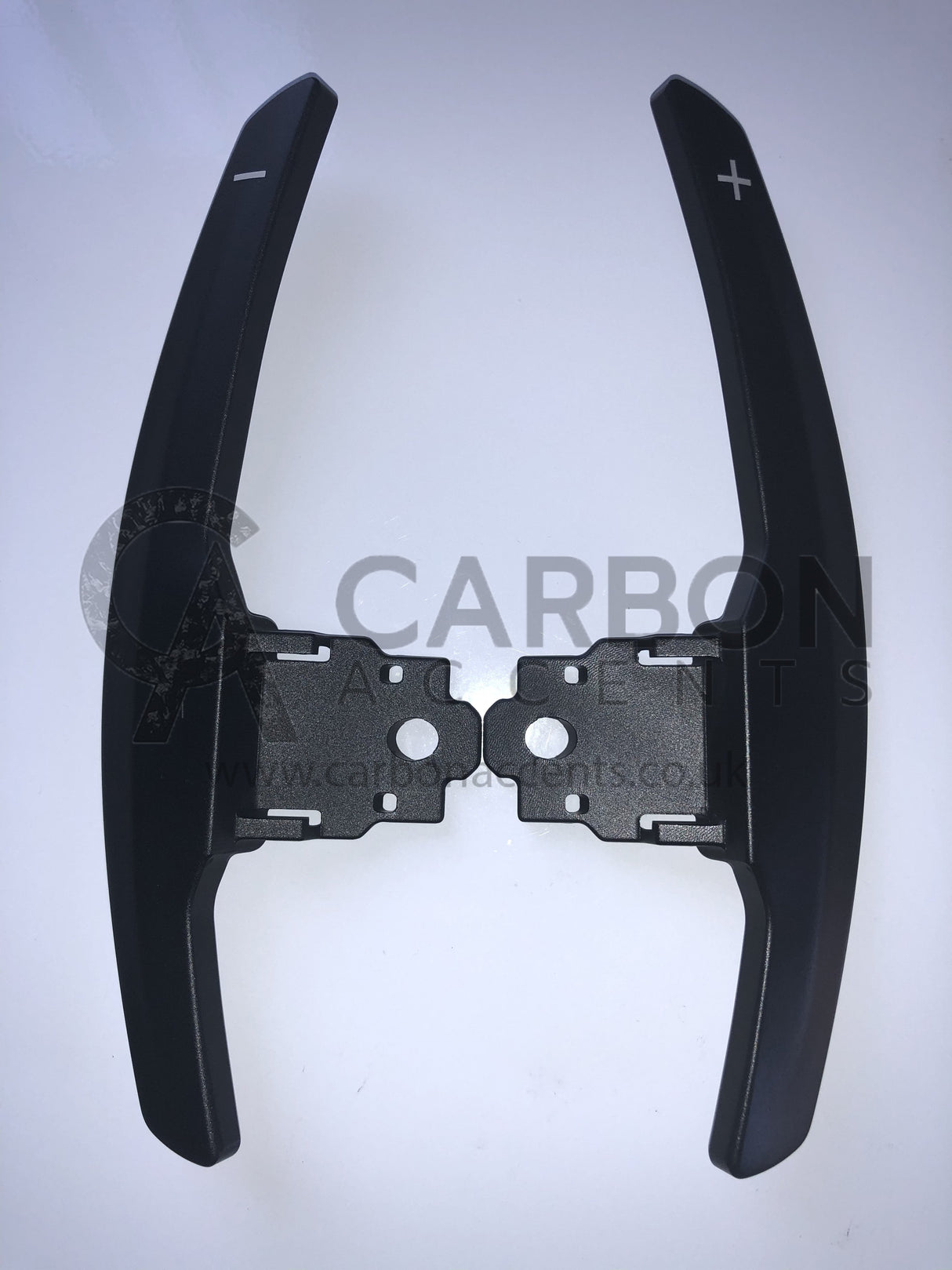 Paddle shifters with plus and minus symbols are displayed against a white background. The text reads, "CARBON ANCENTS www.carbonacents.co.uk."