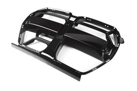A black, glossy, plastic car grille lies on a white background. It features multiple elongated openings and a symmetrical design, designed for automotive airflow and aesthetic enhancement.