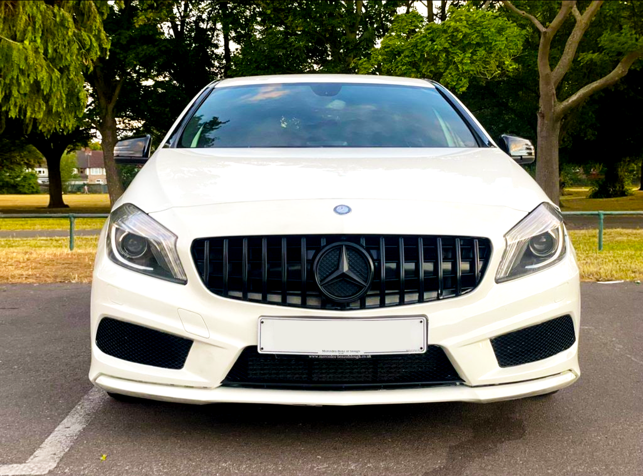 White car with a black grille and circular emblem, parked in an outdoor setting surrounded by lush green trees and a clear sky. License plate text: "Mercedes Benz of Ipswich www.mercedes-benzofipswich.co.uk".