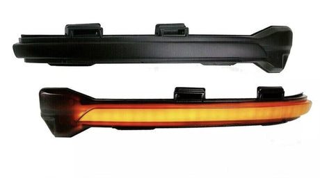 Two black automotive light fixtures are shown. The top fixture is unlit, while the bottom fixture emits a continuous amber glow. Both have mounting brackets and are isolated on a white background.