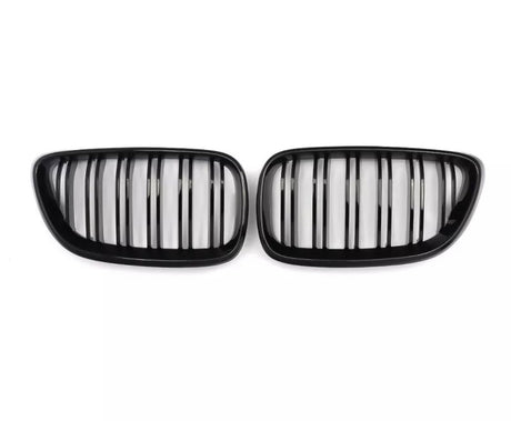 Two black kidney-shaped car grilles with vertical slats, positioned side by side against a plain white background.