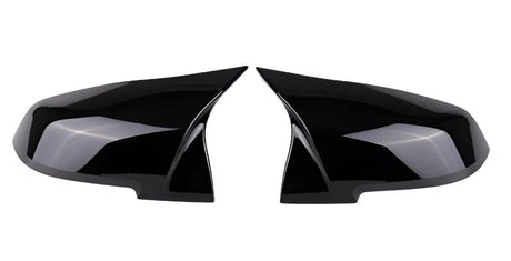 Two glossy black, aerodynamic mirror covers are displayed, positioned symmetrically facing each other, against a plain white background.