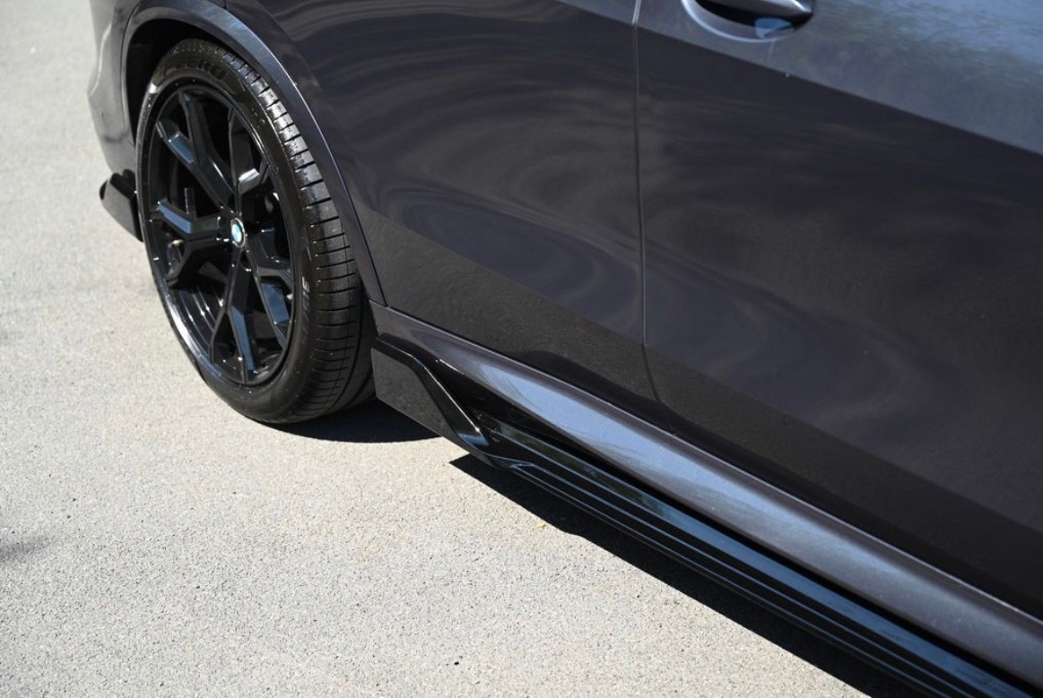 Car door with glossy black trim and wheel, parked on a smooth asphalt surface in sunlight.