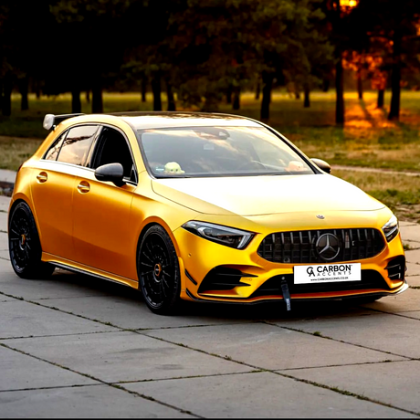 Yellow car parked, featuring black grille and wheels, with a "CARBON ACCENTS" license plate. Surrounding trees create a serene park atmosphere illuminated by warm sunlight.