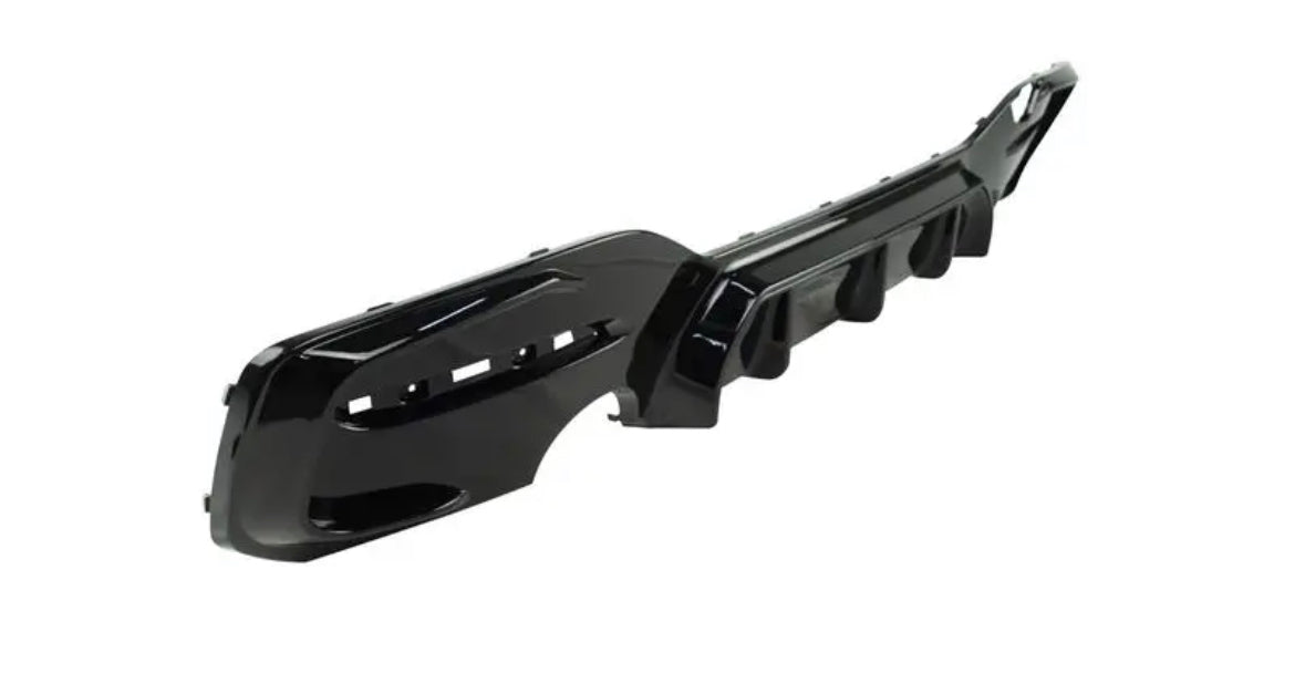 A glossy black car bumper with vent openings lies on a plain white background, displaying an angular, aerodynamic design.