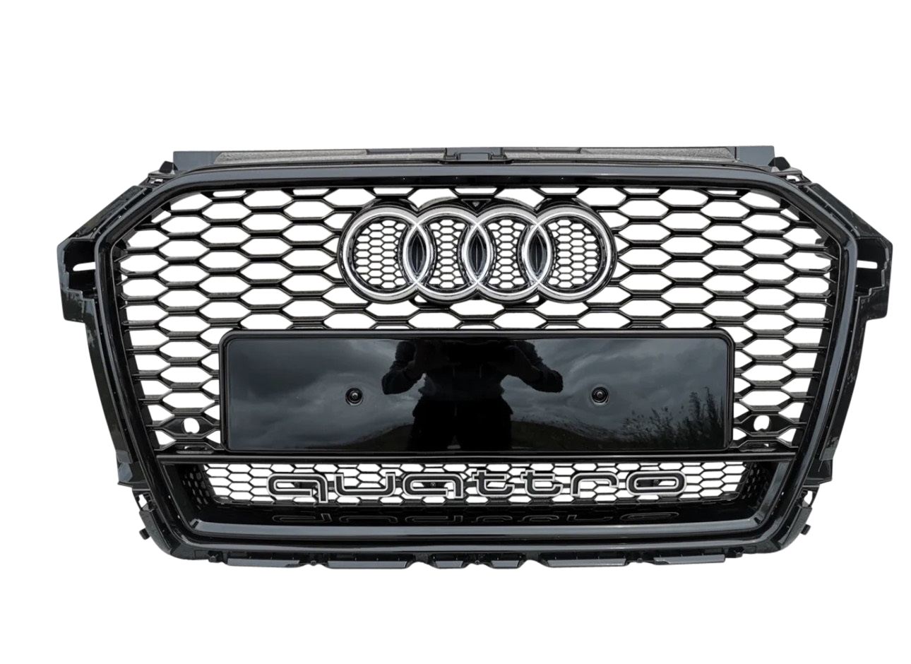 A car grille features a honeycomb pattern, with the Audi logo and the word "quattro" prominently displayed on a metallic surface, set against a gray background.