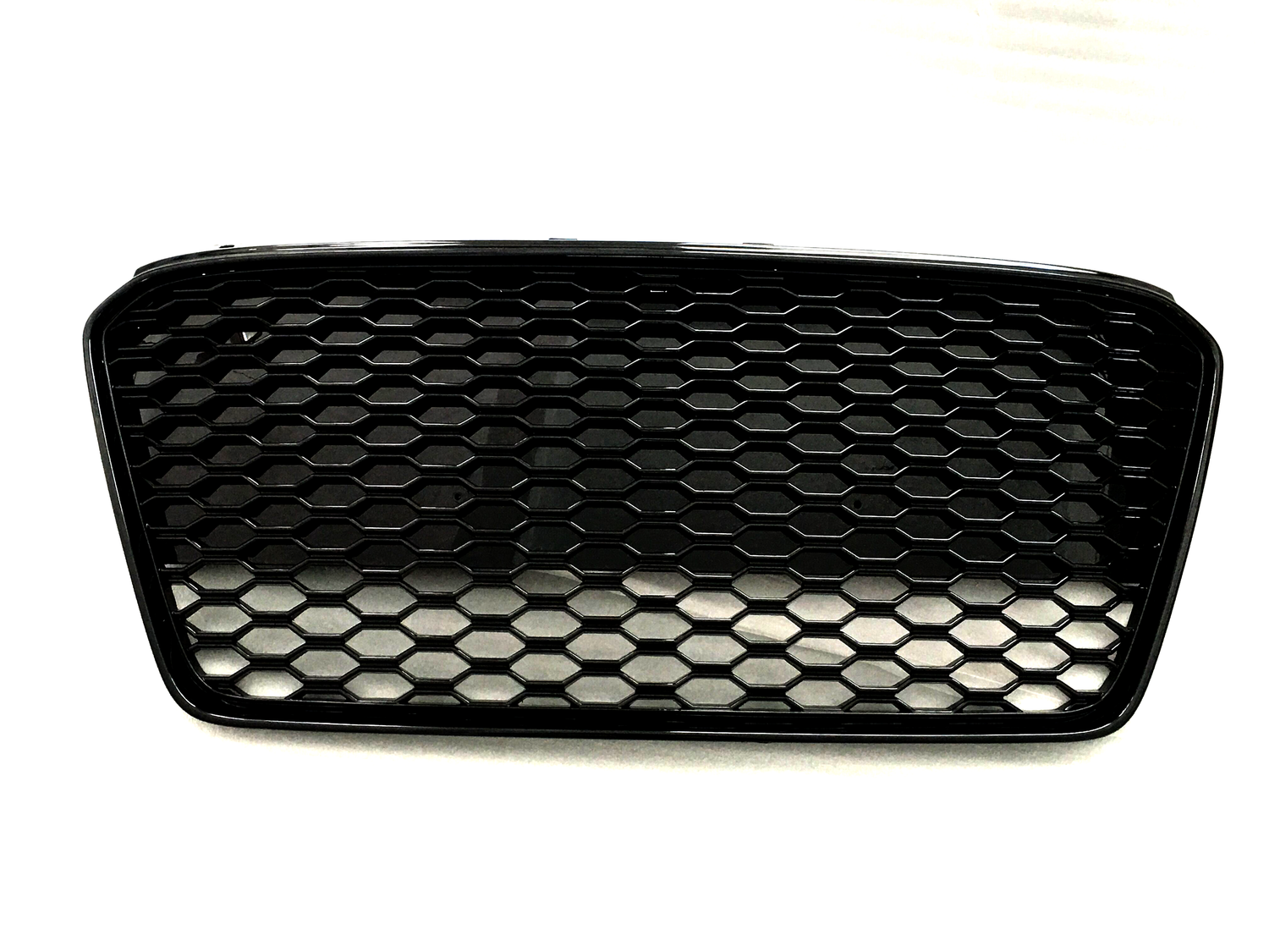 A black car grille with a honeycomb pattern sits against a plain white background.