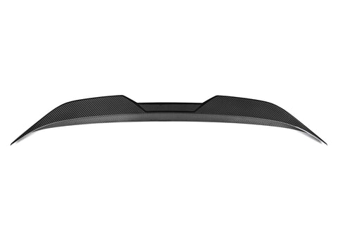 A sleek carbon fiber car spoiler sits against a white background, with a curved and aerodynamic design, featuring angular edges and textured surface details.