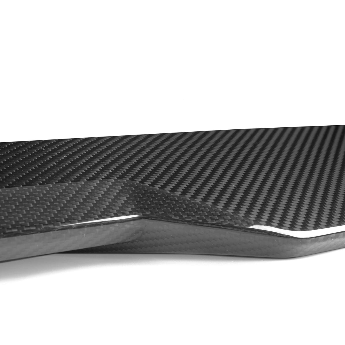 A sleek carbon fiber piece, displaying a glossy, woven texture, rests on a plain white background, emphasizing its modern design and intricate pattern.