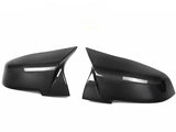 Two black carbon fiber side mirror covers are positioned facing each other against a plain white background, highlighting their sleek, aerodynamic design and glossy finish.