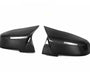 Two black carbon fiber side mirror covers are positioned facing each other against a plain white background, highlighting their sleek, aerodynamic design and glossy finish.