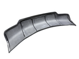 A curved, black carbon fiber rear diffuser with aerodynamic design sits against a white background, featuring multiple fins and a textured surface for enhanced vehicle performance.