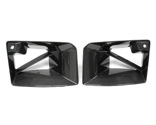 Two black, angular, carbon-fiber car exhaust trims with cutout designs are placed side by side against a plain white background.