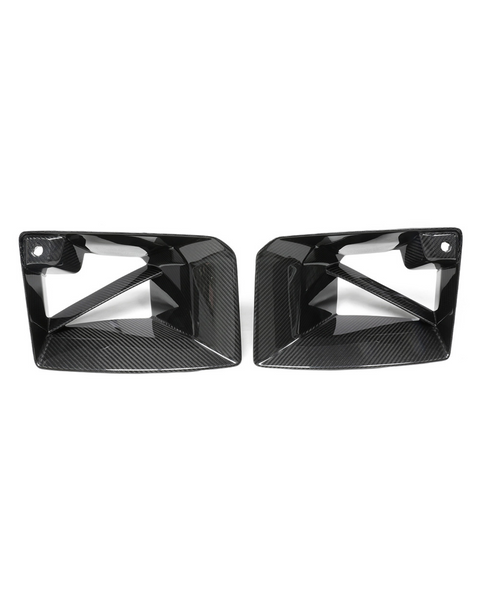 Two black, angular, carbon-fiber car exhaust trims with cutout designs are placed side by side against a plain white background.