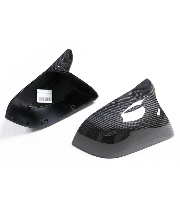 Two carbon fiber car mirror covers are displayed on a white background. One cover is upright, the other flipped, showing an internal barcode sticker.