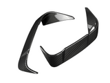 Two carbon fiber car parts with a sleek, aerodynamic design are positioned against a plain white background, displaying a glossy, reflective surface pattern.