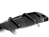 Carbon fiber car part with raised fins, resting on a white surface, featuring a glossy, patterned design and mounting holes.