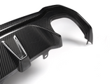A carbon fiber car part with angled attachments lies on a plain white background, showcasing its textured surface and precision design.