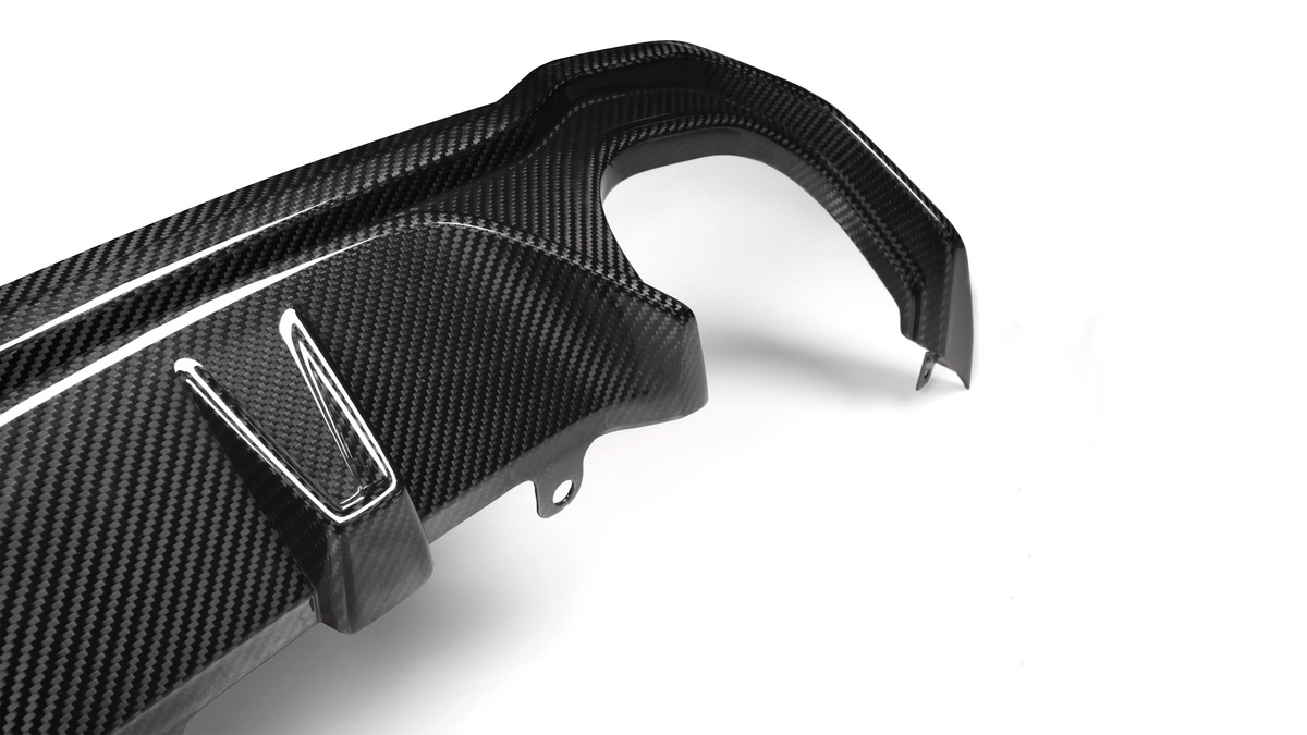 A carbon fiber car part with angled attachments lies on a plain white background, showcasing its textured surface and precision design.