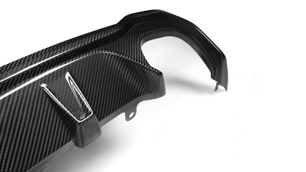 A carbon fiber car part with angled attachments lies on a plain white background, showcasing its textured surface and precision design.