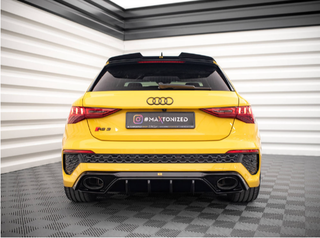 Yellow Audi RS3 car, stationary, viewed from the rear in a showroom with checkered gray flooring and white-striped walls. Text: "#MAXTONIZED."