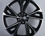 A sleek, glossy black alloy wheel with a multi-spoke design featuring the Audi logo at its center, displayed against a plain gray background on a white platform.