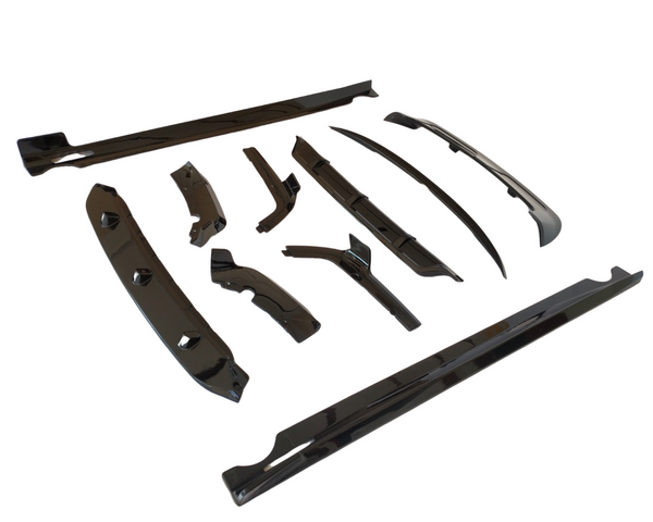 Black glossy car body kit parts are arranged on a plain white background. They vary in shape and size, including side skirts, bumpers, and fenders, showcasing their aerodynamic design.