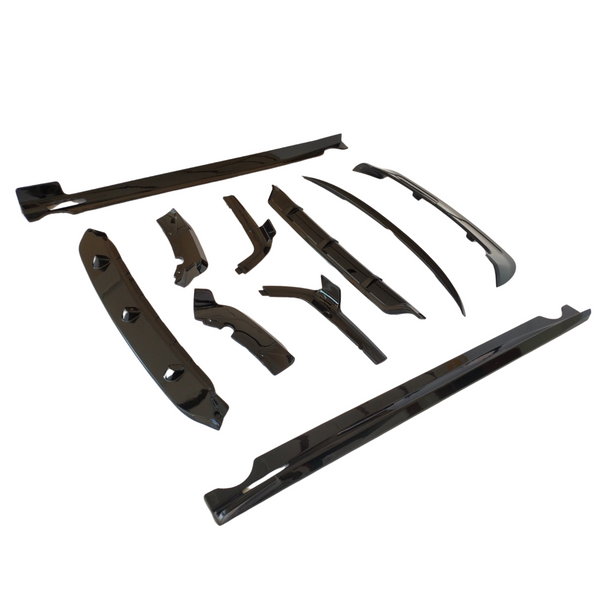 Black glossy car body kit parts are arranged on a plain white background. They vary in shape and size, including side skirts, bumpers, and fenders, showcasing their aerodynamic design.