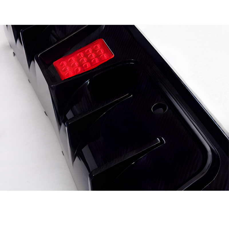 A black car bumper features a small rectangular red reflector and a circular hole, set on a white background.