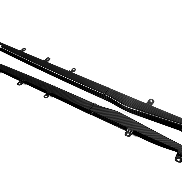 Two long, black carbon fiber car side skirts with mounting brackets lie on a white background. One piece features the text "500000."