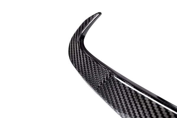 A curved carbon fiber piece, possibly a car spoiler, is shown against a plain, white background, highlighting its textured pattern and sleek design.