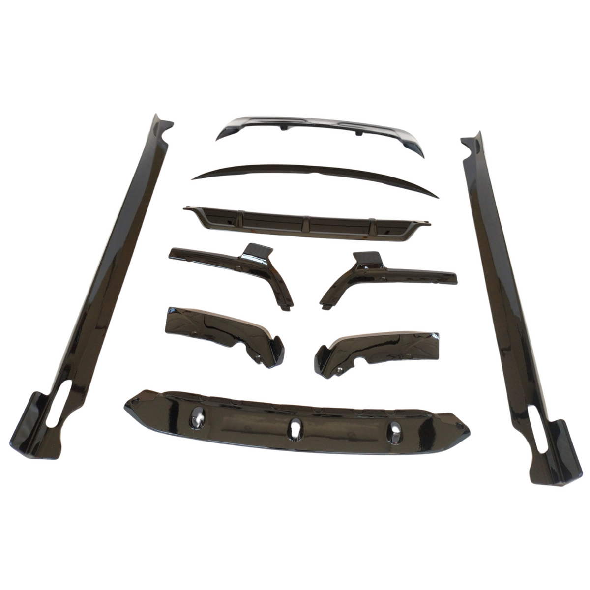 Car body kit components arranged on a white background, including aerodynamic parts like side skirts, bumpers, and wing pieces, all sleek and glossy, designed for vehicle customization.