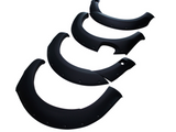 Four black, matte-finish fender flares are arranged in a staggered formation. Each piece is curved with rivet details and is set against a plain white background.