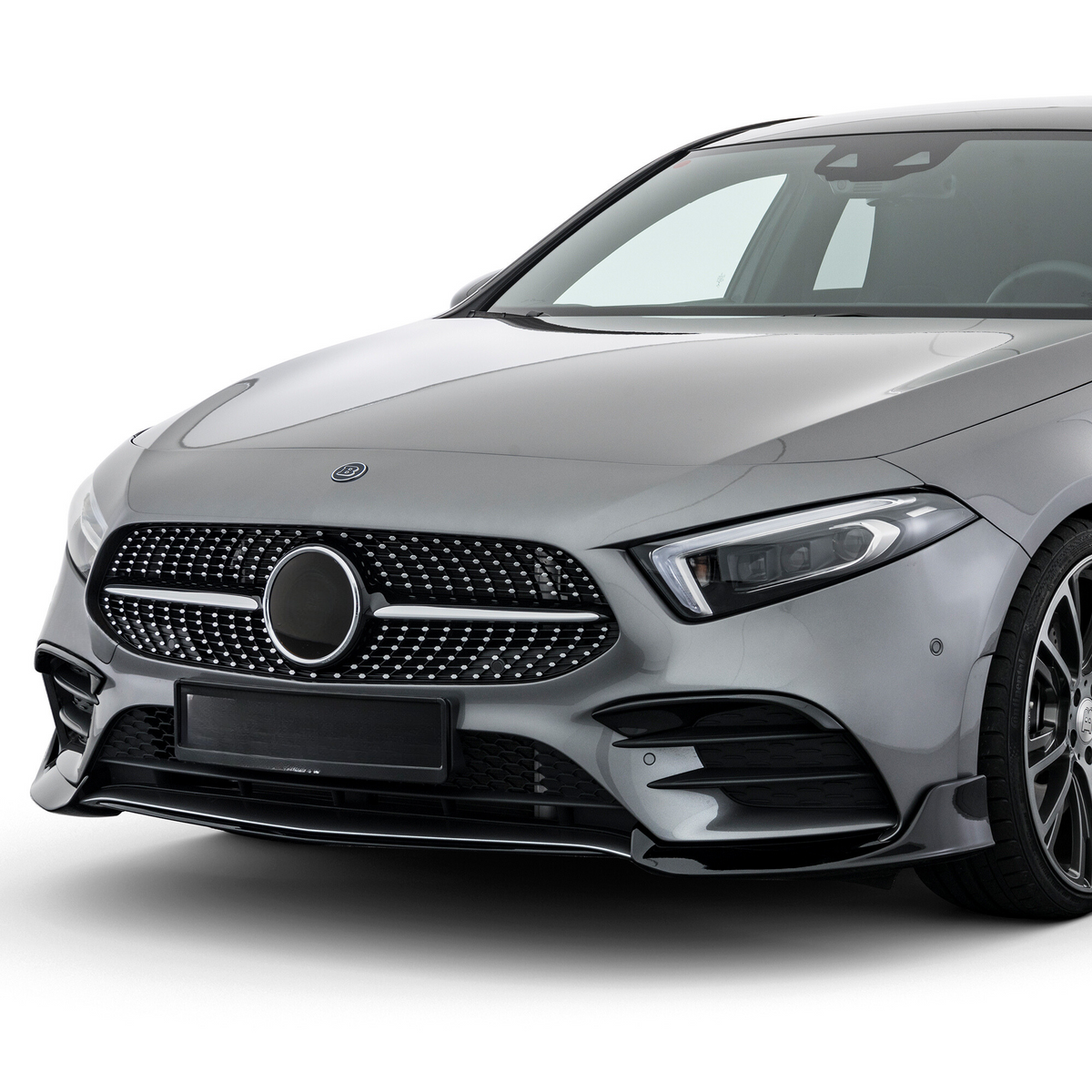 A sleek silver car showcases a stylized front grille and modern headlights, positioned in a well-lit studio, highlighting its glossy finish and elegant design lines.
