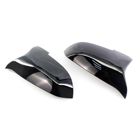 Black, glossy car mirror covers are shown lying side by side on a white background, reflecting light and their smooth, curved design.