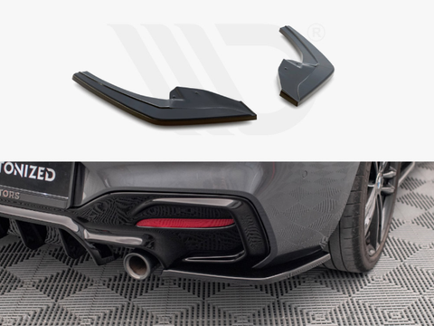 Two black aerodynamic car diffusers are displayed above a rear view of a car on a patterned floor, with an exhaust pipe and diffuser installed.