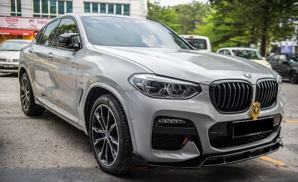 A gray BMW with sleek lines is parked in a lot, surrounded by other vehicles and trees, with a badge on the front grill.