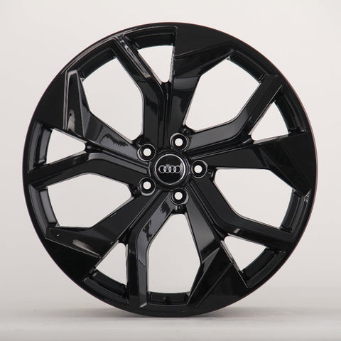 A glossy black alloy wheel with a five-spoke design featuring the Audi logo at the center, sits against a plain white background.